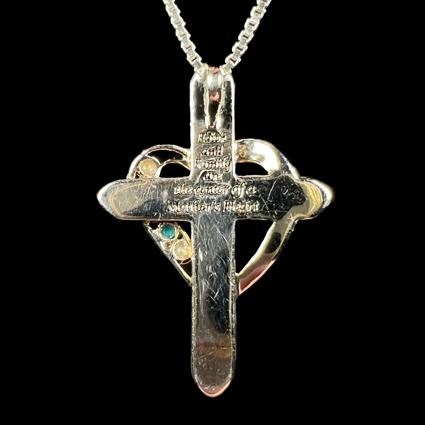 Back side of a sterling silver mother's cross pendant, showing an engraving.