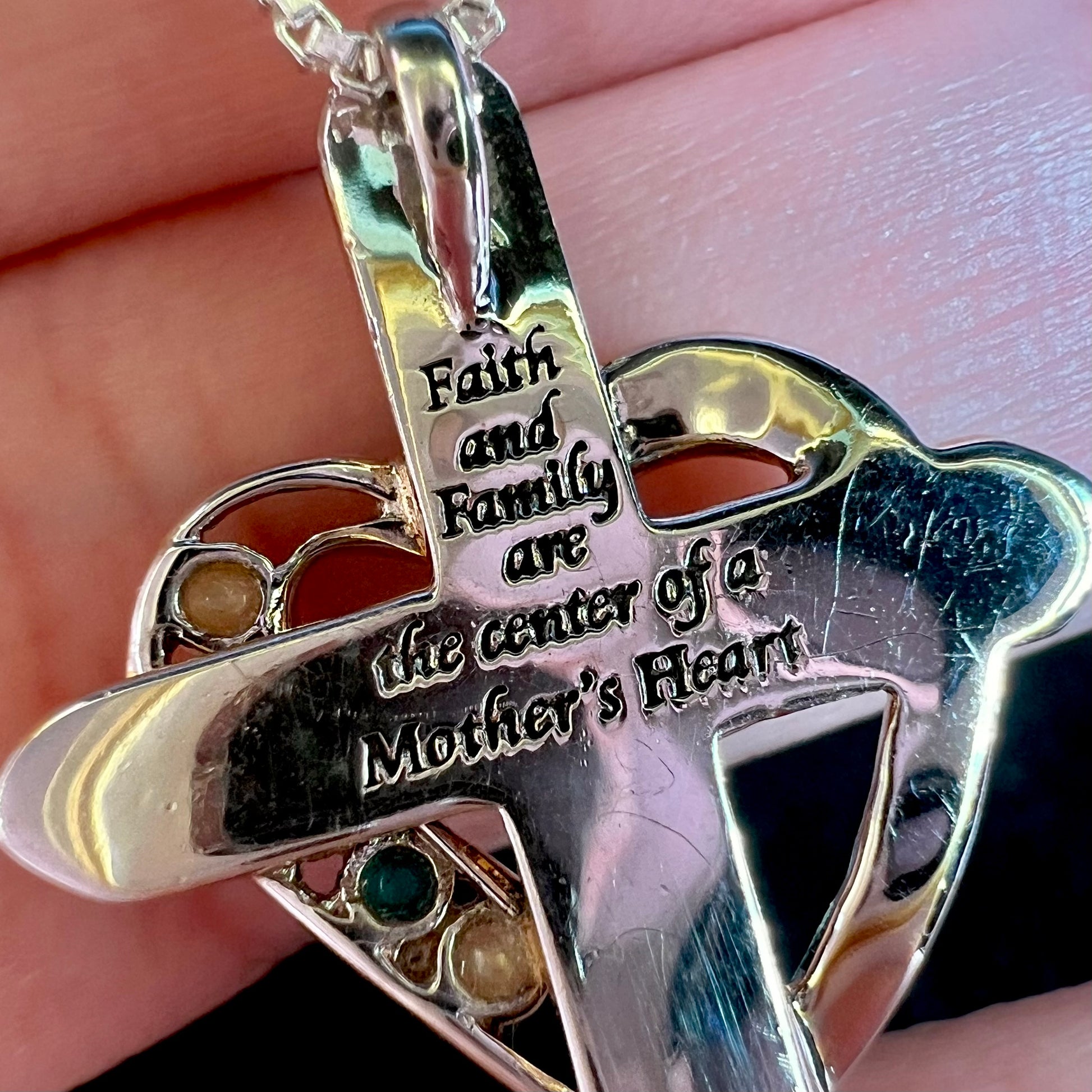 Back of a sterling silver cross pendant engraved, "Faith and Family are the center of a other's Heart".