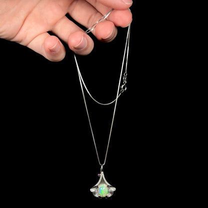 Hand dangling sterling silver Ethiopian opal ginko leaf-style necklace from chain