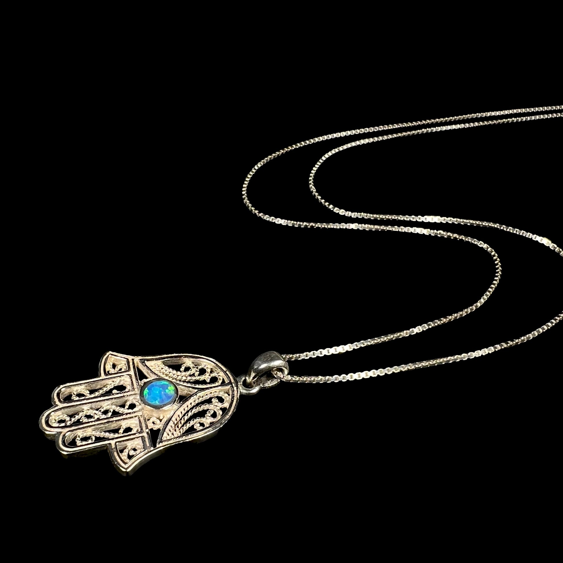 A sterling silver and filigree-accented hamsa hand necklace set with a round lab-created opal.