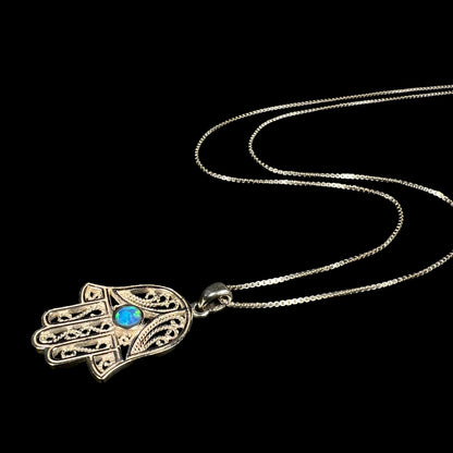 A sterling silver and filigree-accented hamsa hand necklace set with a round lab-created opal.