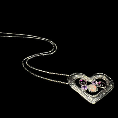 A sterling silver heart necklace set with a round Ethiopoian opal, two amethysts, and two rhodolite garnets.