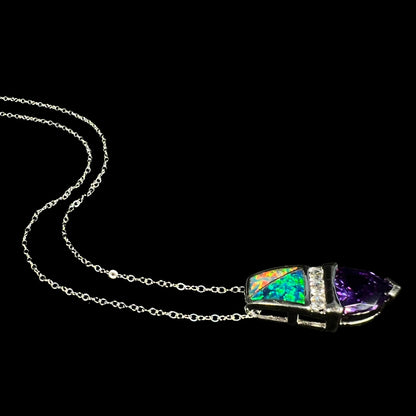 Angled side view of a sterling silver lab-created opal inlay and purple trillion cut CZ drop necklace, laying on a black background with its chain flowing behind the pendant.