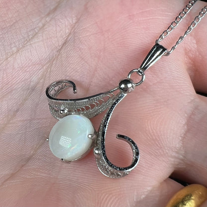 A Sorrento brand sterling silver Australian white opal pendant shown close-up from an angle in a hand.