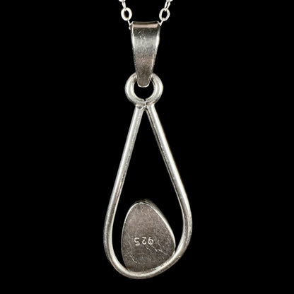 Back side of Modernist-style sterling silver opal doublet pendant, shown on chain against black backdrop.  "925" is seen on the pendant.