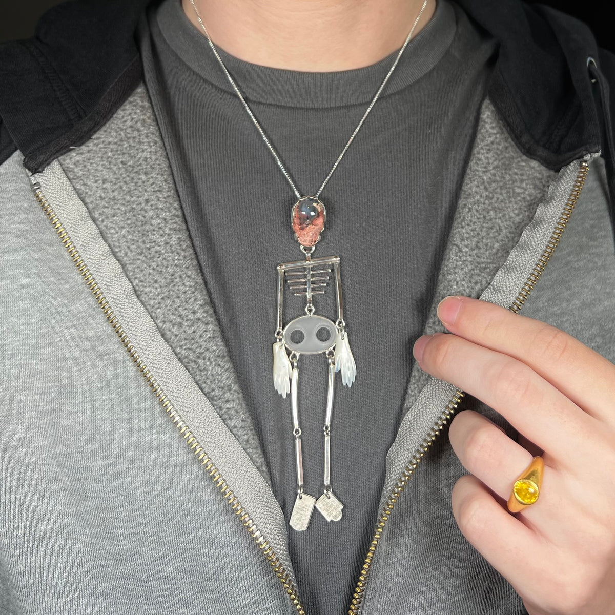 Person wearing a large sterling silver skeleton statement necklace with Mexican cantera opal skull around neck against dark shirt