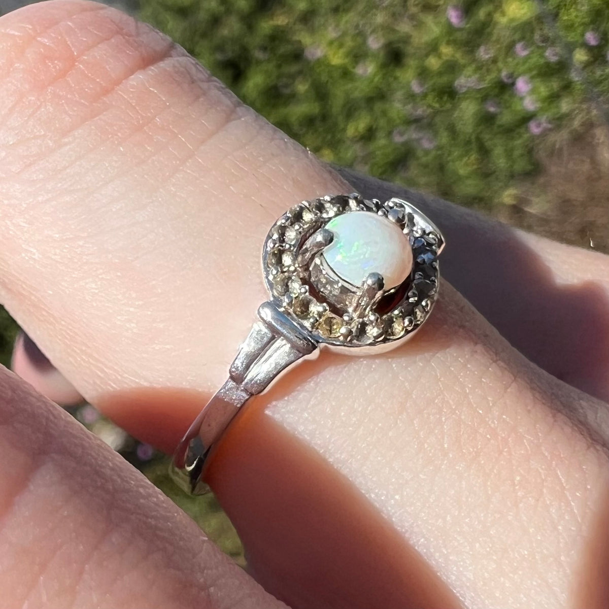 Sterling silver shank in focus, viewing opal and smoky quartz ring from macro angle on finger in sunlight