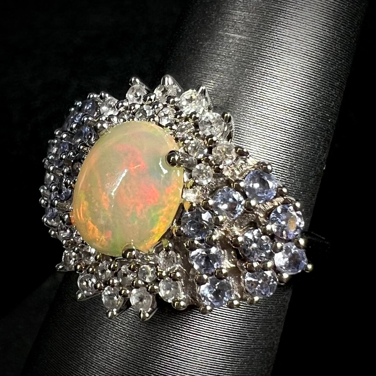 Angled close-up of sterling silver fire opal, tanzanite, and topaz cluster ring on display