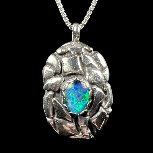 Front of a sterling silver pinecone-inspired opal triplet pendant, shown against a black background.