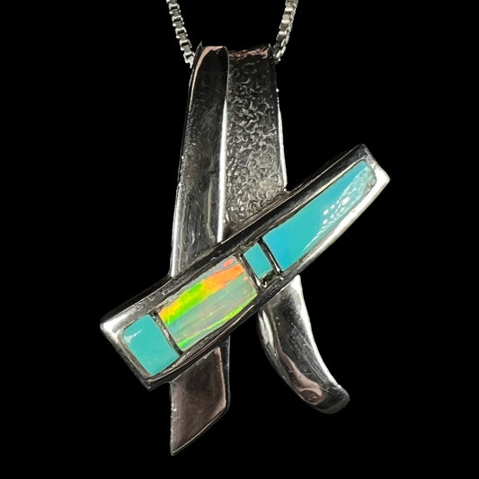 A folded design sterling silver turquoise and lab-created opal inlay pendant shown close-up.