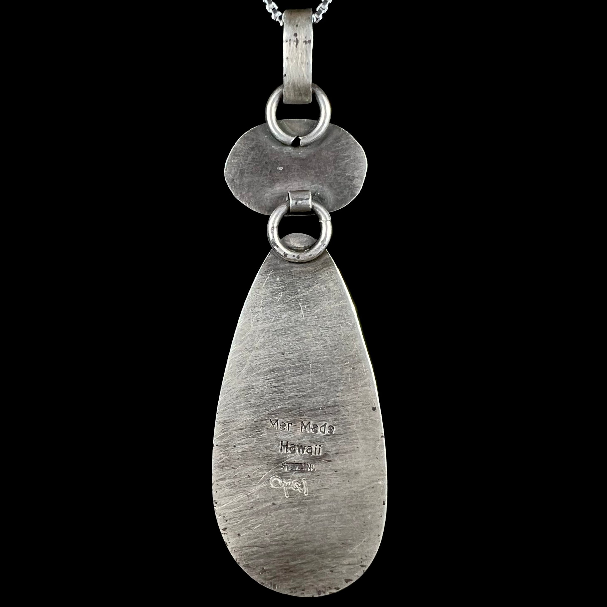 Back side of sterling silver pendant stamped "Mer Made Hawaii STERLING" and etched with the word "Opal".