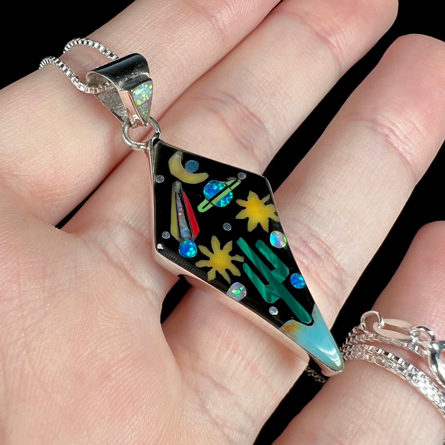Colorful Philippines-made Southwest-style sterling silver gemstone inlay pendant shown front an angle held in hand.