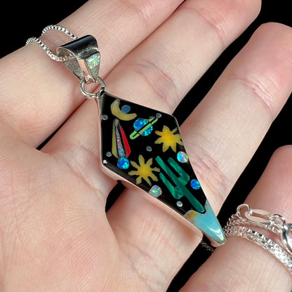 Colorful Philippines-made Southwest-style sterling silver gemstone inlay pendant shown front an angle held in hand.