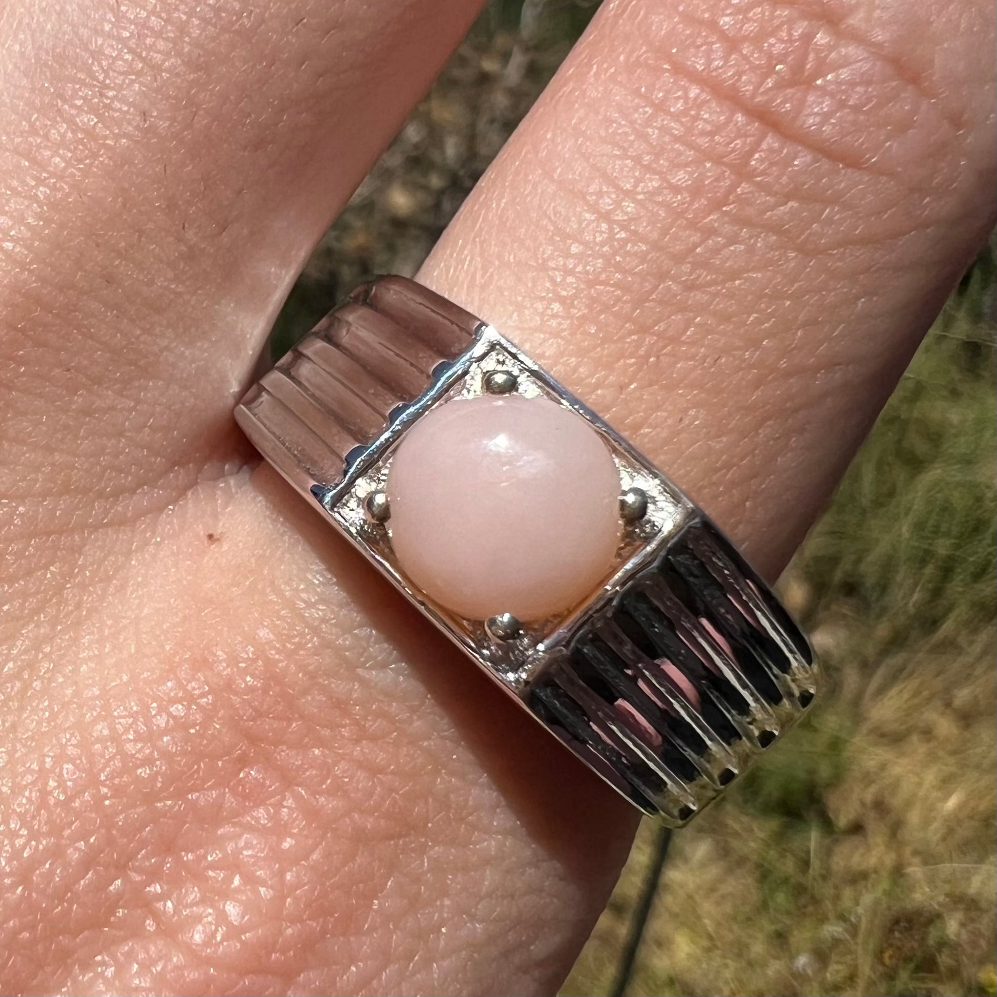 Close-up of sterling silver pink Peruvian opal ring in sunlight on finger