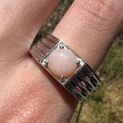 Close-up of sterling silver pink Peruvian opal ring in sunlight on finger