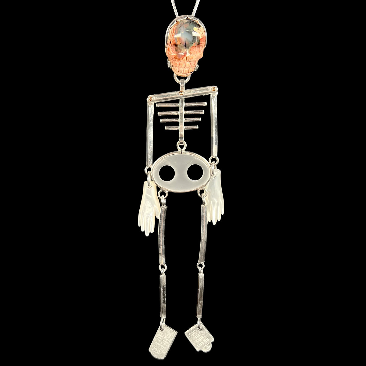 Sterling silver skeleton pendant with carved opal skull and moving bones hanging vertically on silver chain