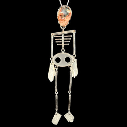 Sterling silver skeleton pendant with carved opal skull and moving bones hanging vertically on silver chain