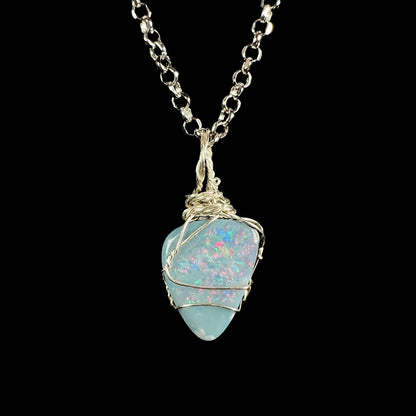 A dainty women's sterling silver wire wrapped Australian dark opal doublet pendant on a steel cable chain, shown against black background.