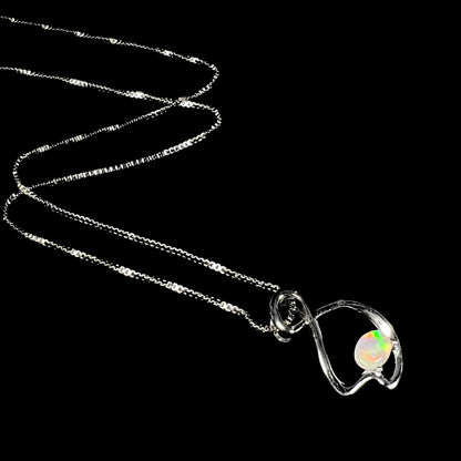 A ladies' sterling silver necklace set with an oval cabochon cut natural white crystal opal with green fire.