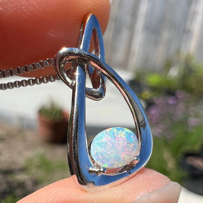 A ladies' sterling silver pendant set with an oval cabochon cut natural white crystal opal.