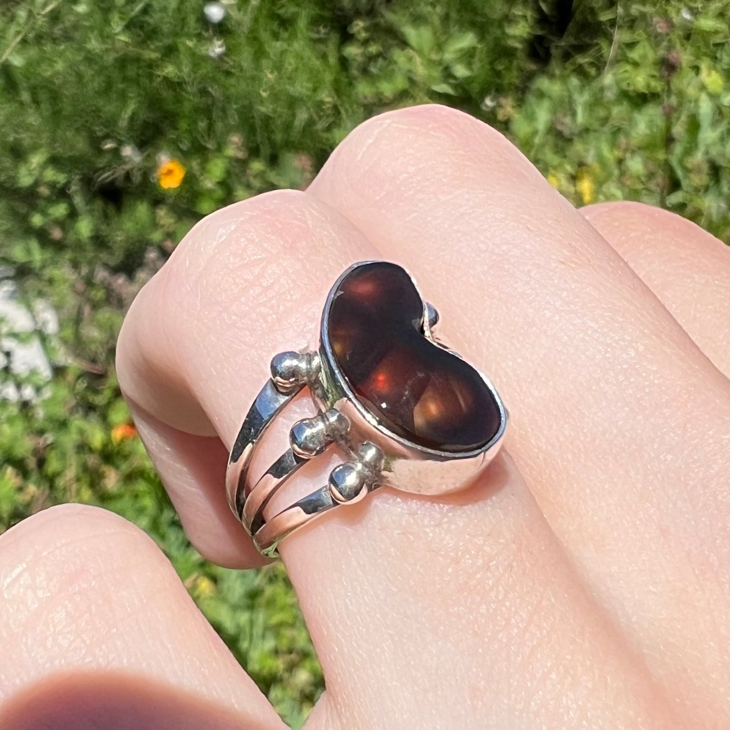 Side angle of fire agate ring in sunlight showing warm iridescence.