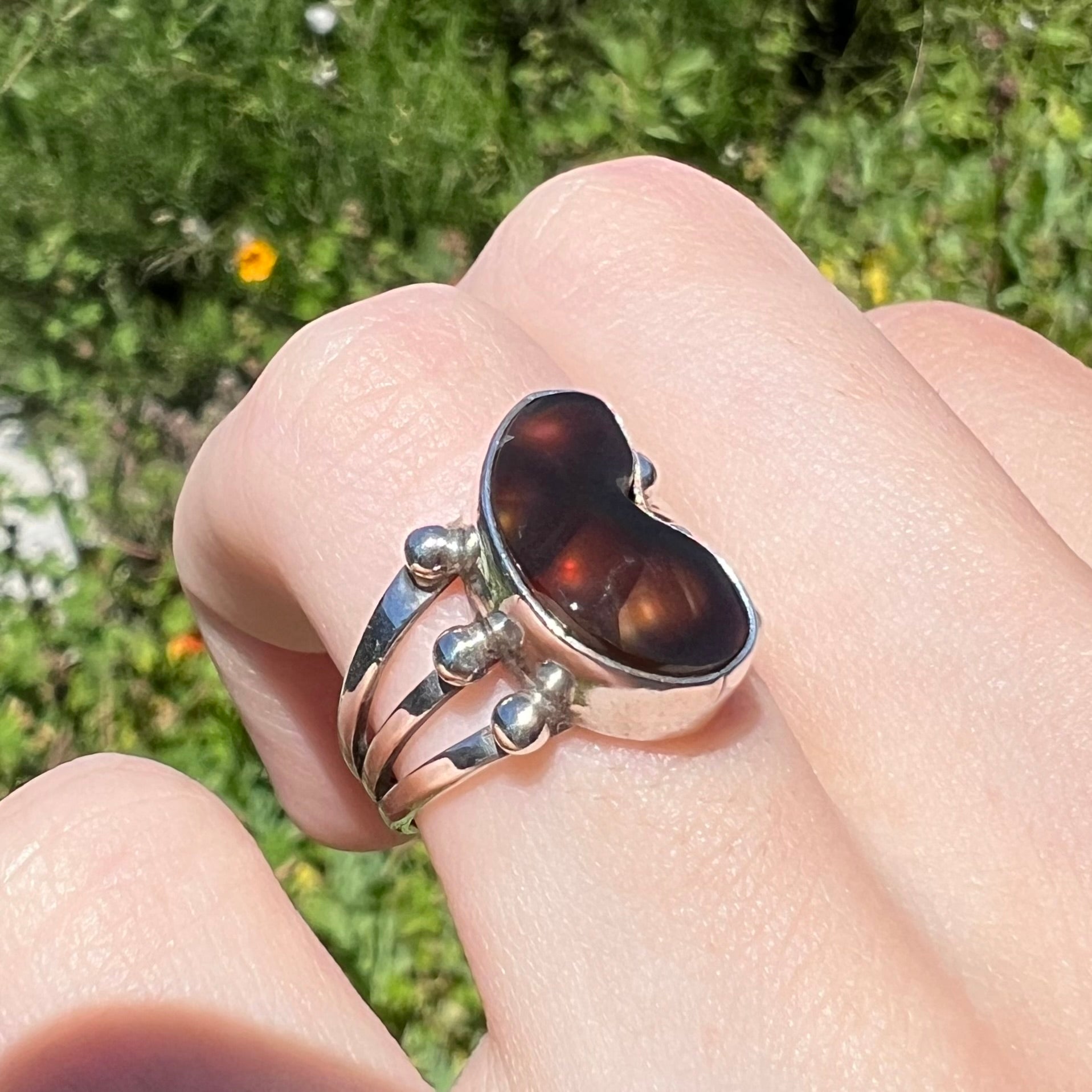 Side angle of fire agate ring in sunlight showing warm iridescence.
