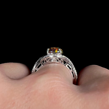 A lab-created black opal solitaire ring in sterling silver with filigree, shown from the gallery view on a hand.