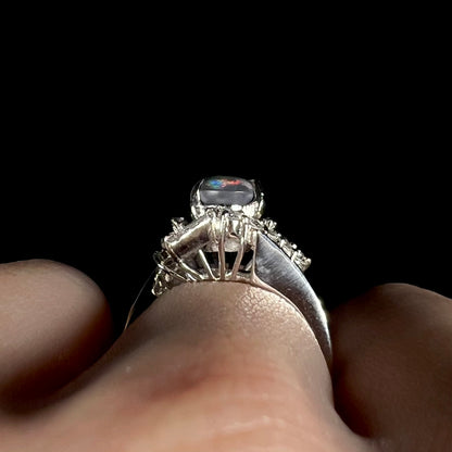 Side gallery view of a tall, vintage Japanese platinum opal ring, worn on hand.
