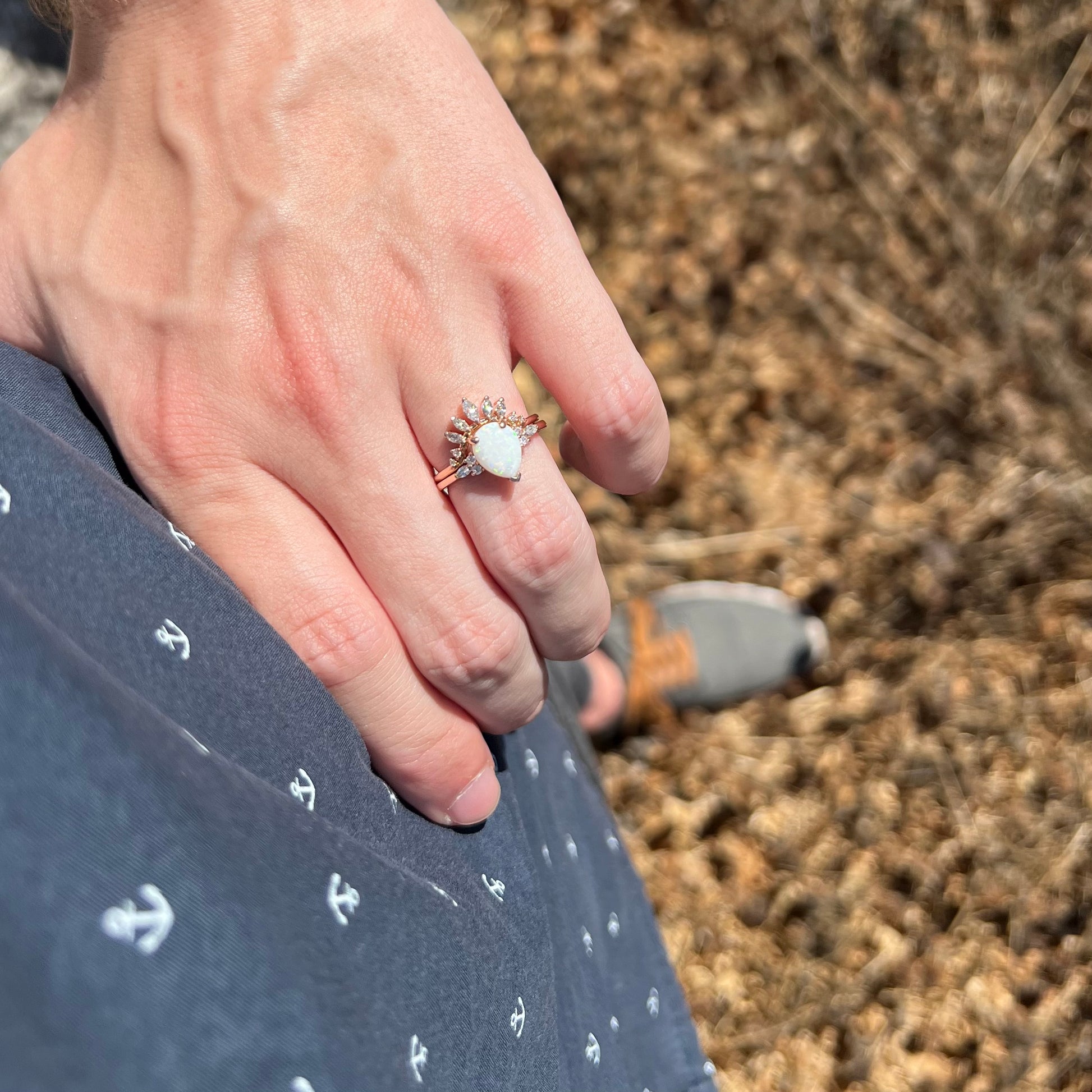 Hand resting on hip in sunlight while wearing a rose gold teardrop-shaped opal and moissanite wedding ring set