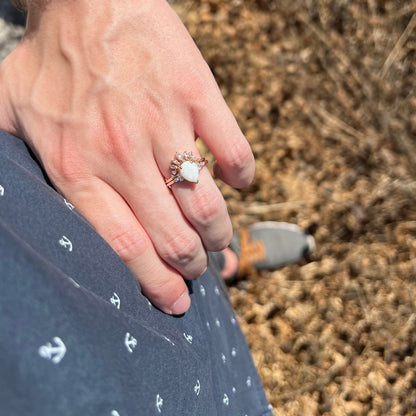 Hand resting on hip in sunlight while wearing a rose gold teardrop-shaped opal and moissanite wedding ring set