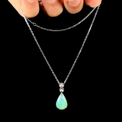 A platinum drop pendant mounted with two diamond accents and a pear shaped green-blue crystal opal.