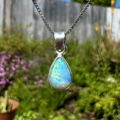A dainty, sterling silver necklace bezel set with a natural, pear shaped opal stone.
