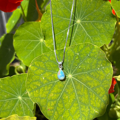 A dainty, sterling silver necklace bezel set with a natural, pear shaped opal stone.