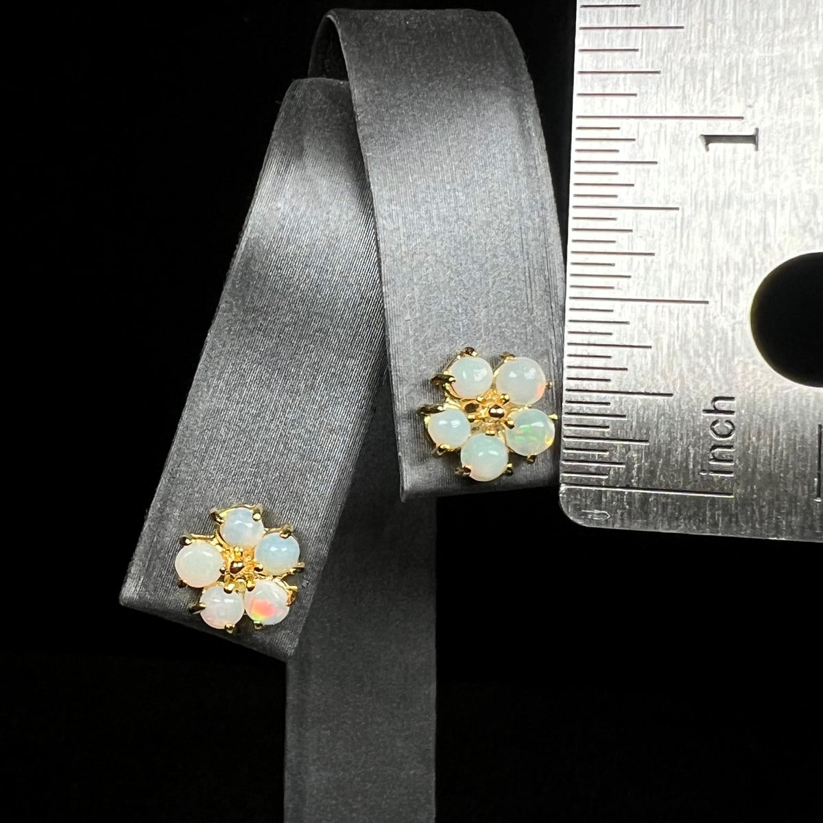 Pair of opal flower earrings on earring display next to ruler measuring one-third of an inch long