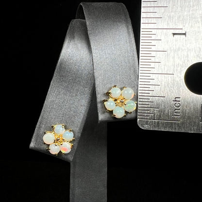 Pair of opal flower earrings on earring display next to ruler measuring one-third of an inch long