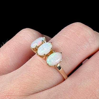 A vintage yellow gold ring mounted with three oval cut white Australian opals.