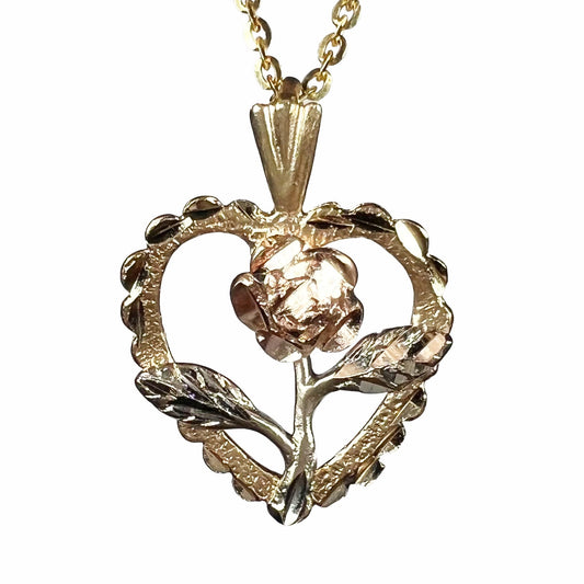 A tricolor gold pendant featuring the design of a heart with a flower in the middle of it.