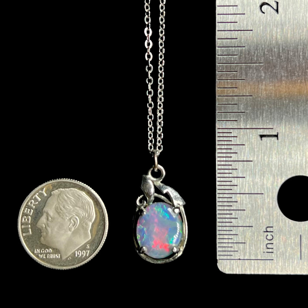 Base metal triplet opal pendant measuring 0.9 inch long, shown between US dime coin and ruler for scale