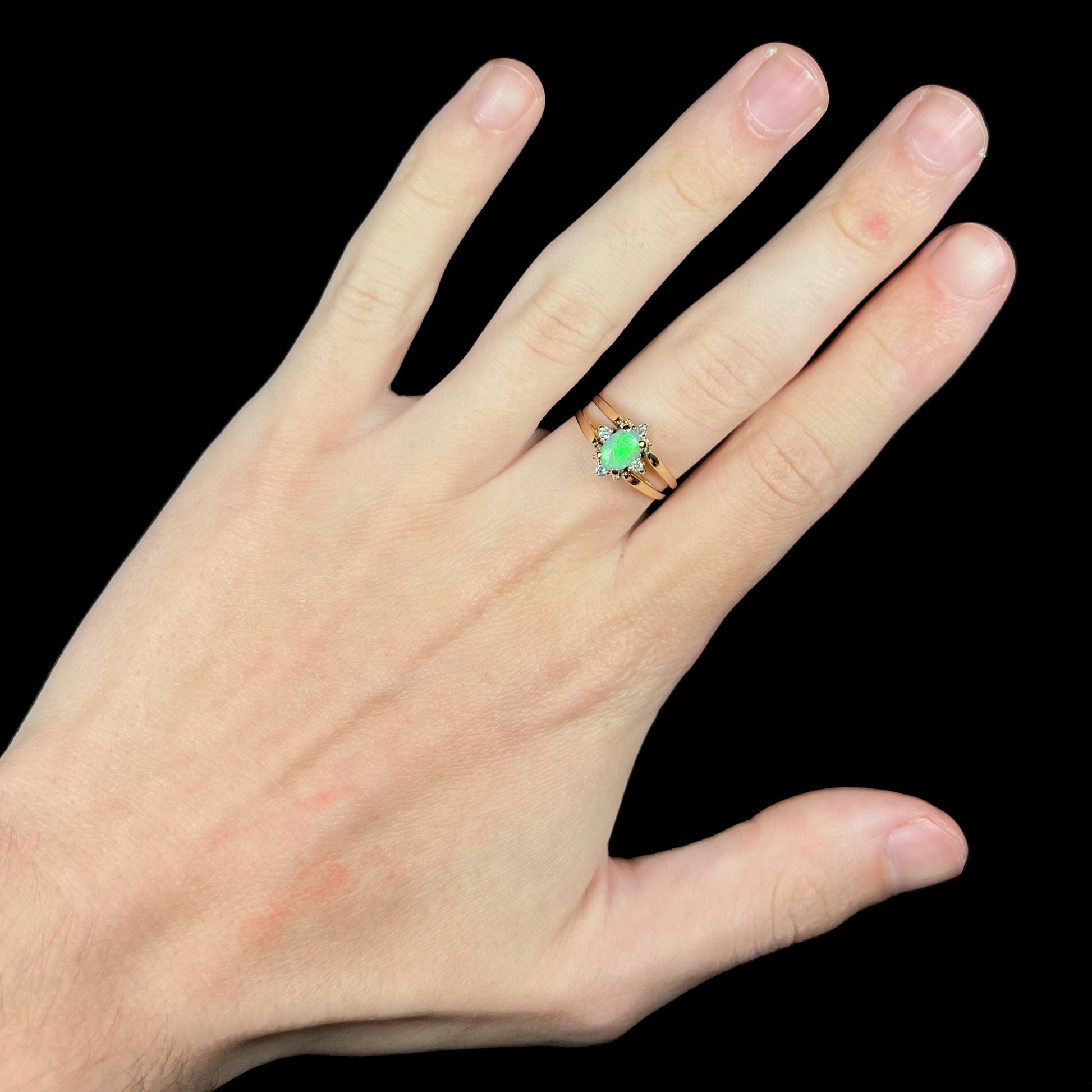 Hand wearing two-sided opal and diamond flip ring in 14k gold