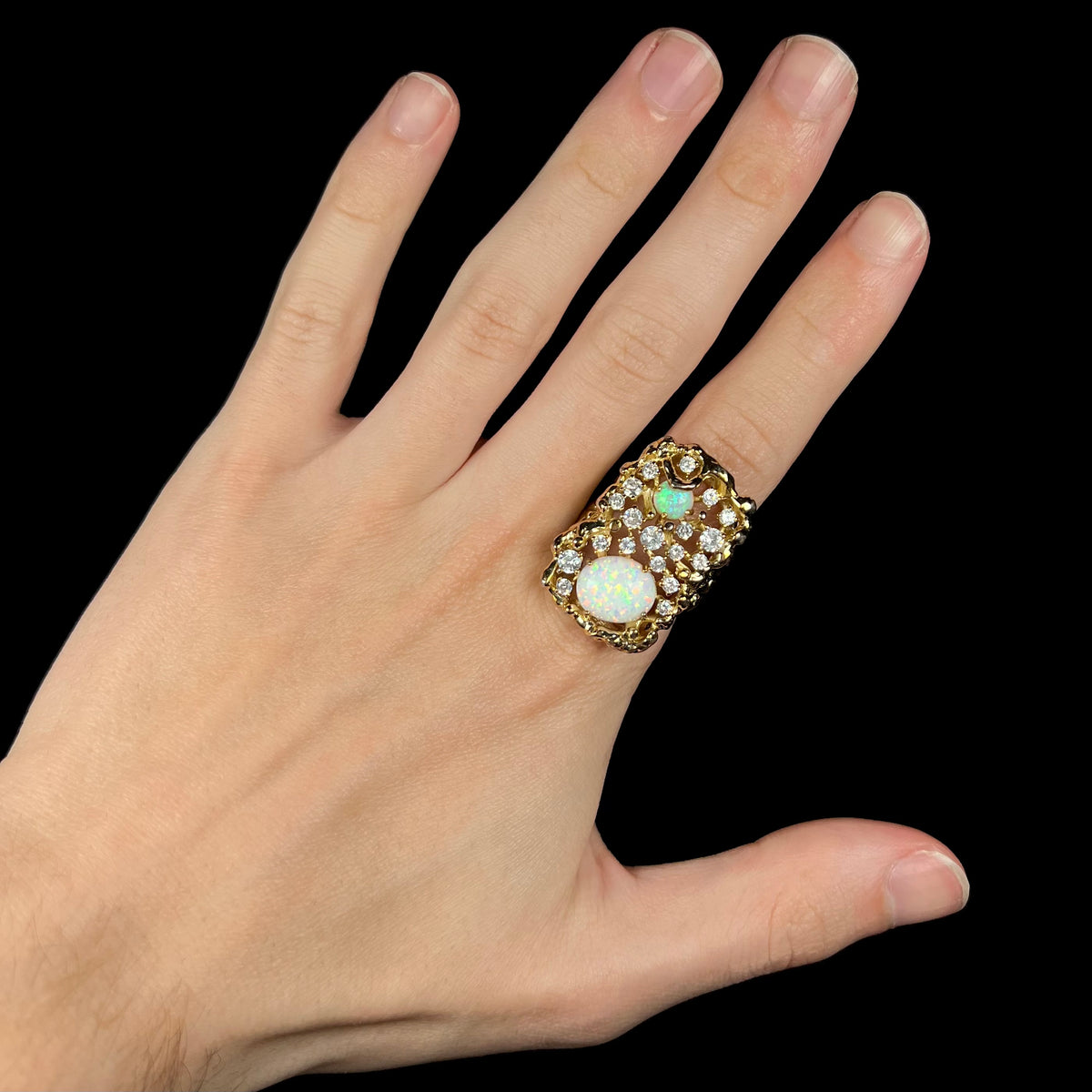 Hand wearing large two-stone lab-created opal and CZ statement ring on index finger.