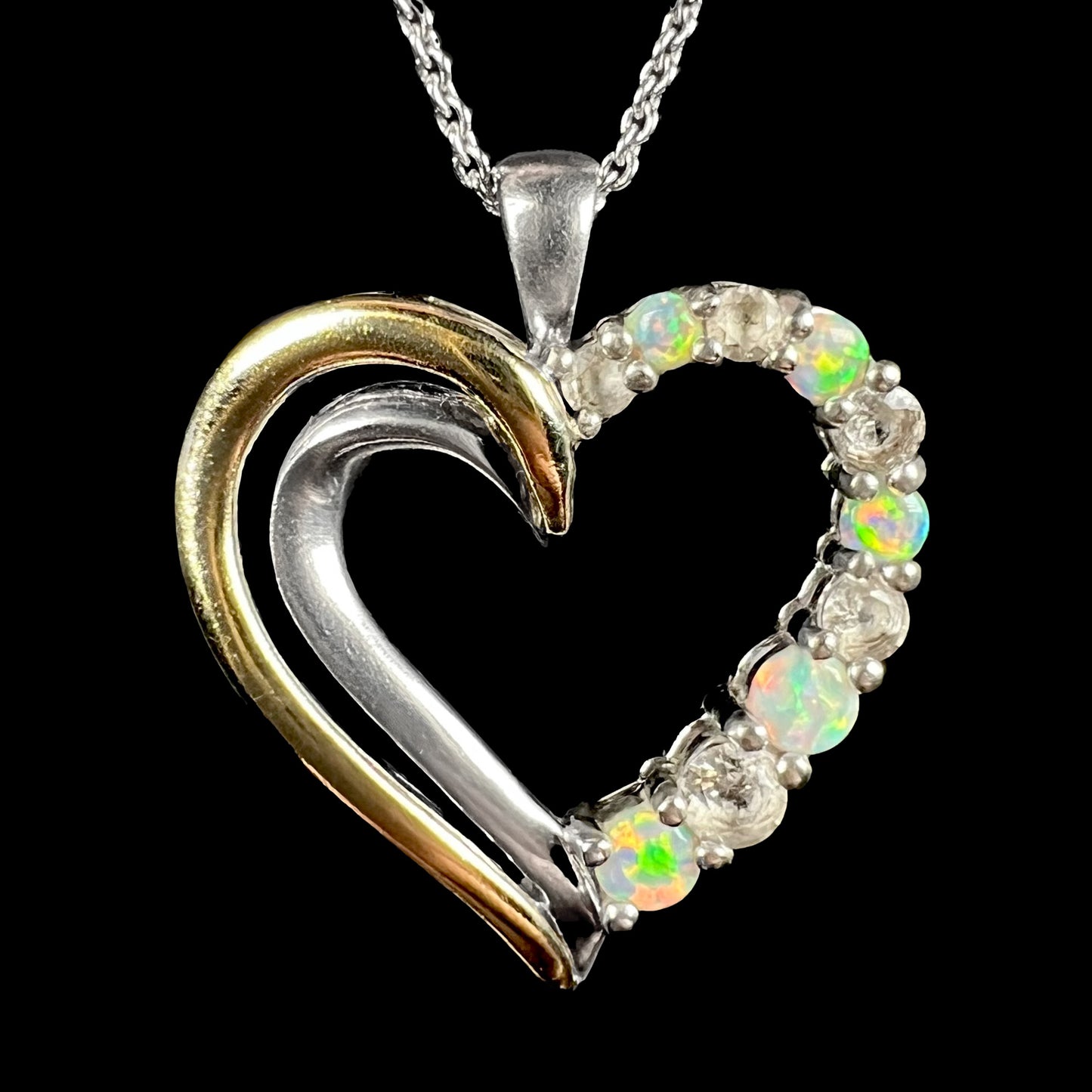 A two-tone sterling silver and yellow gold lab-created opal and CZ heart necklace, shown close-up.
