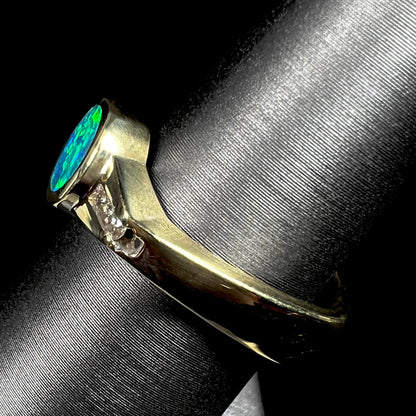 Side view focusing on the Euro shank of a unisex 18k yellow gold boulder opal ring, shown close-up on a ring display.