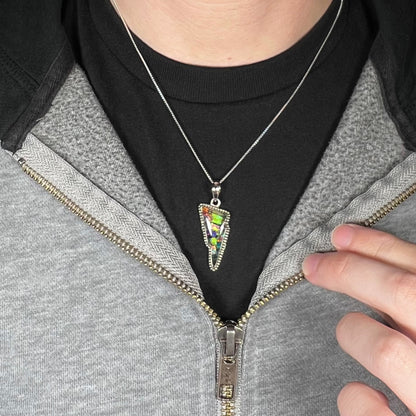 Close-up of person's neck and chest wearing a unisex stering silver lightning bolt necklace worn against dark shirt and partially unzipped hoodie.