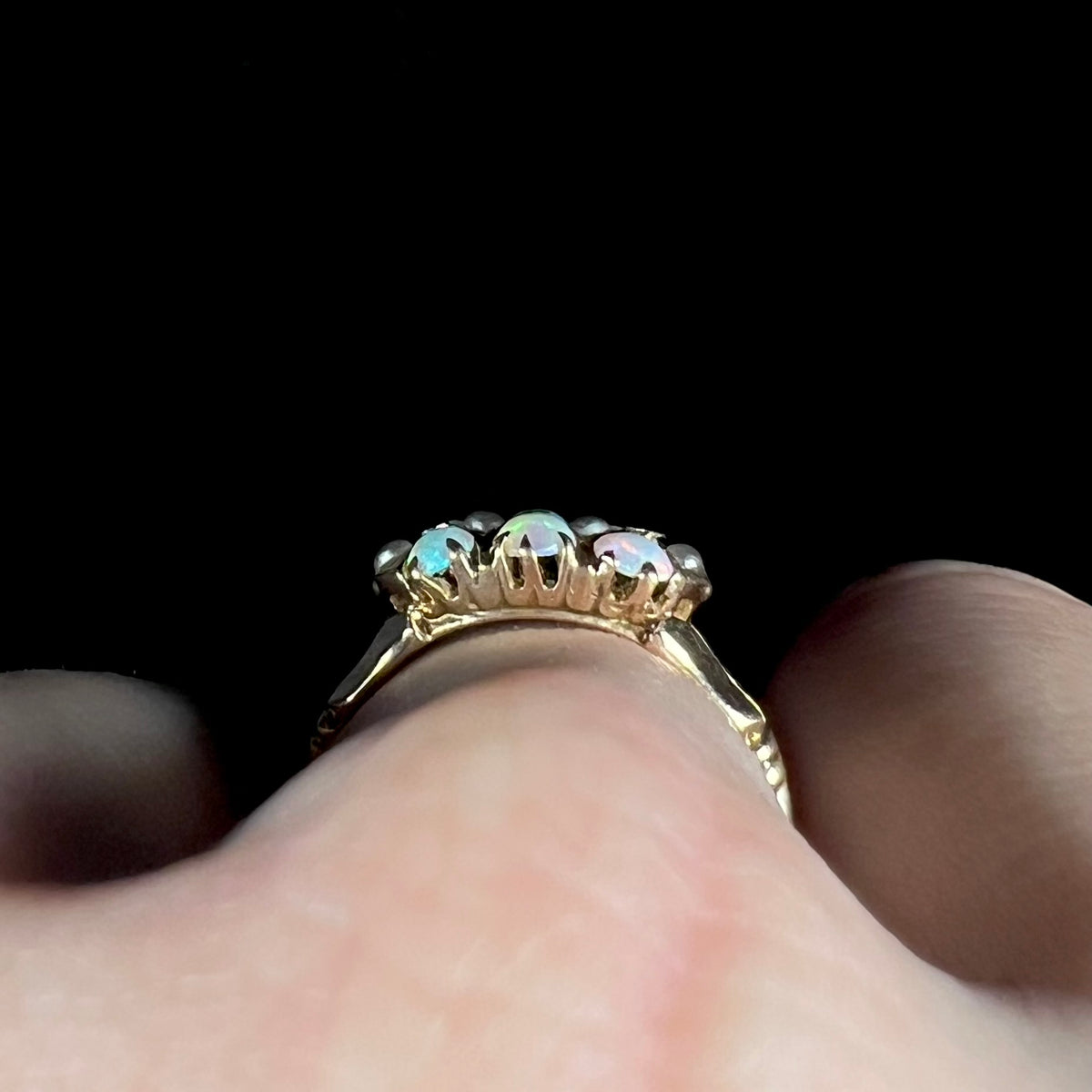 Victorian prong-set opal ring worn on hand and viewed from side gallery profile view; one pearl accent appears to be lifting from the setting