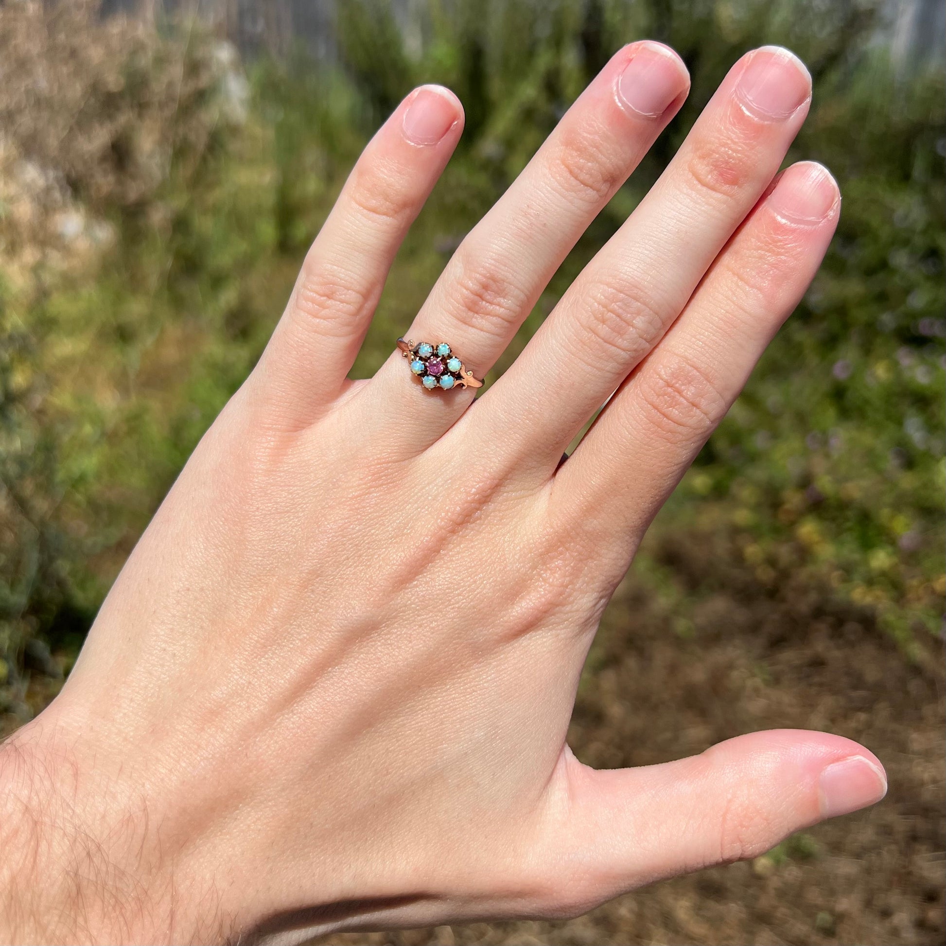 1880s era Victorian women's opal and pink tourmaline cluster ring in 9k gold, worn on hand under natural light