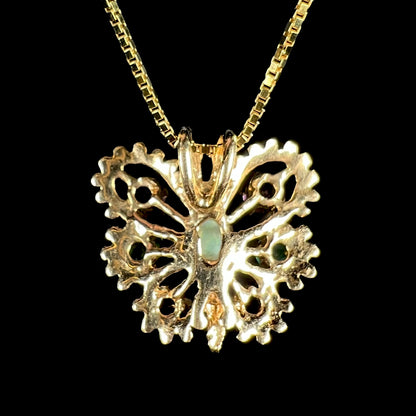 Back side of a vintage 14k yellow gold butterfly pendant on box-style chain against black background.