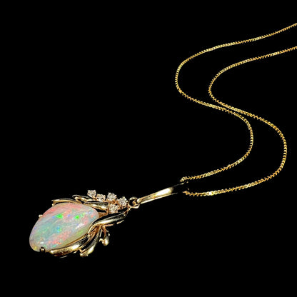 A vintage 1980s era Australian opal necklace with diamond accents in 14k yellow gold, shown from angled view with chain splayed against black background.