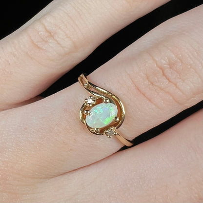 Close-up of a vintage 1990s 10k gold Australian opal and diamond engagement ring worn on a finger.