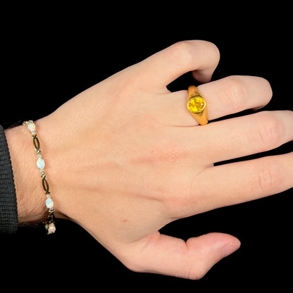 Hand wearing ring on finger and a vintage 1990s era yellow gold opal tennis bracelet around wrist.