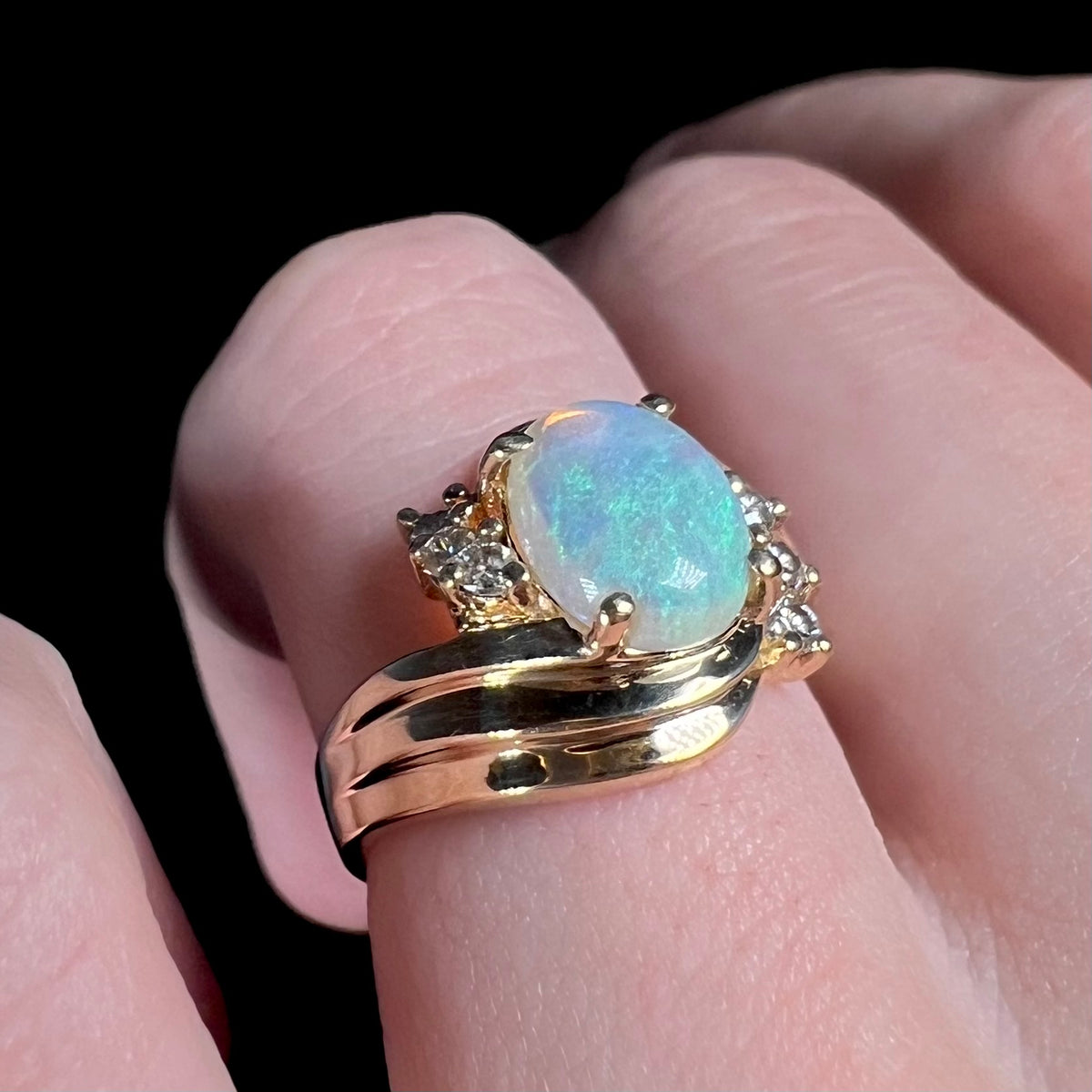 Vintage 14k gold Australian crystal opal and diamond ring worn on finger.  The opal has subtle blue play of color.